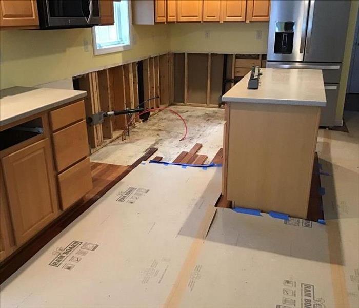 Kitchen lower cabinet detached, wall behind being removed, floor underneath being pulled