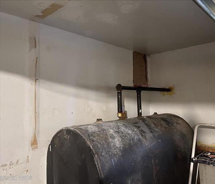 Water damaged garage with wet drywall behind the oil tank